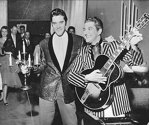 Foto de los lugares de intercambio de Elvis Presley y Liberace en 1956. Los dos artistas cambiaron de chaqueta con Elvis tomando el candelabro de Liberace y Liberace tocando la guitarra de Elvis para una foto publicitaria.  Ambos aparecían en Las Vegas.