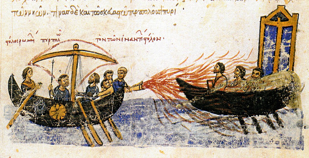 Imagen de un manuscrito iluminado, los Skylitzes de Madrid, que muestra el fuego griego en uso contra la flota de los rebeldes en: Tomás el Eslavo El título sobre el barco de la izquierda dice, ??????  ???????  ????????  ???  ???  ????????  ??????, es decir, "la flota de los romanos incendiando la flota de los enemigos".