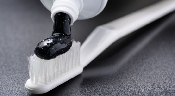 Un cepillo de dientes blanco y una pasta de dientes blanqueadora de carbón negro.